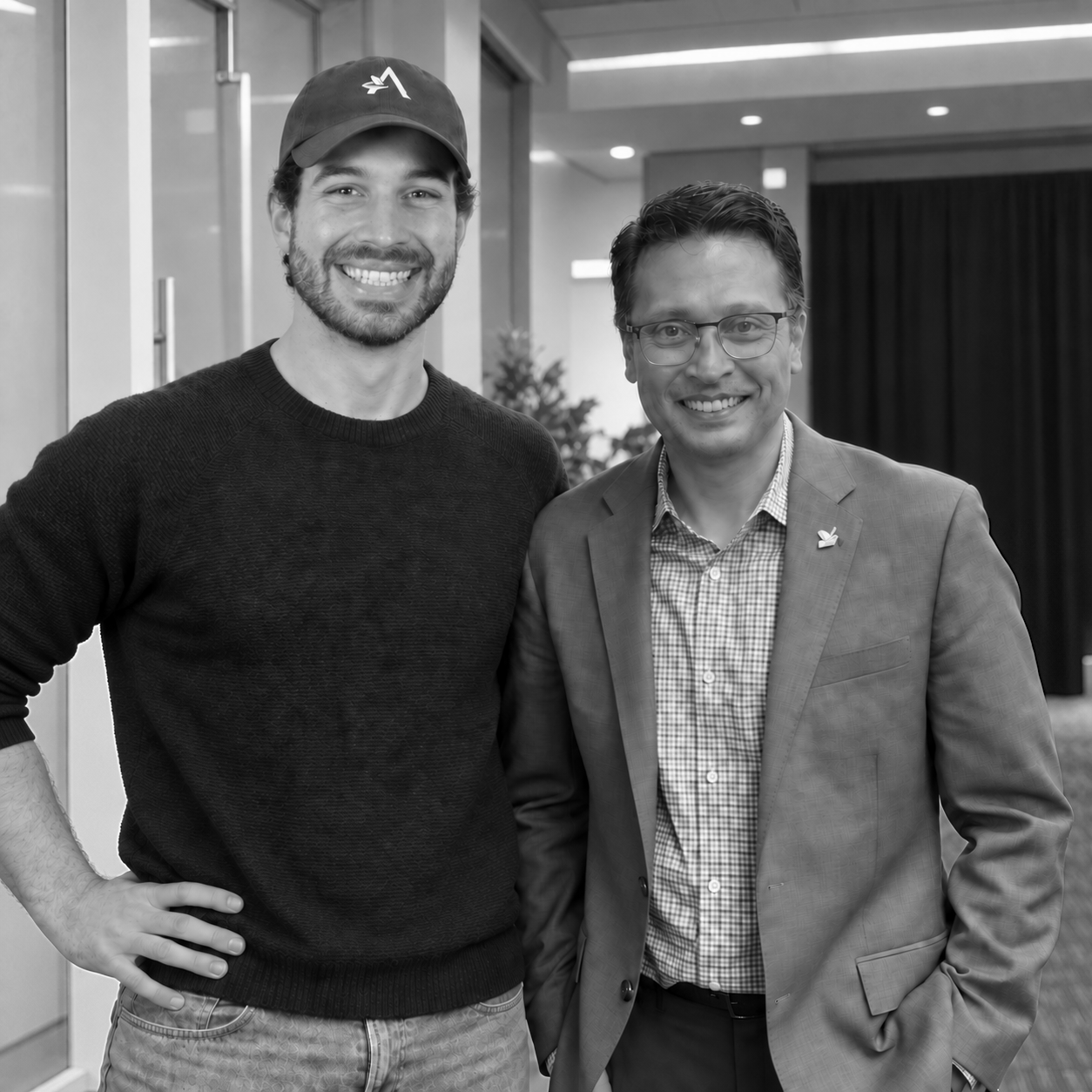 Black-and-white edited photo of Otavio Pailo on the left, wearing a cap and sweater, with Sharran Srivatsaa on the right.